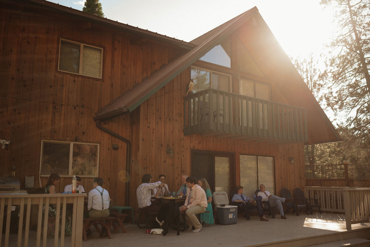 friends and family gather at tables to enjoy a meal after a small elopement at rustic cabin