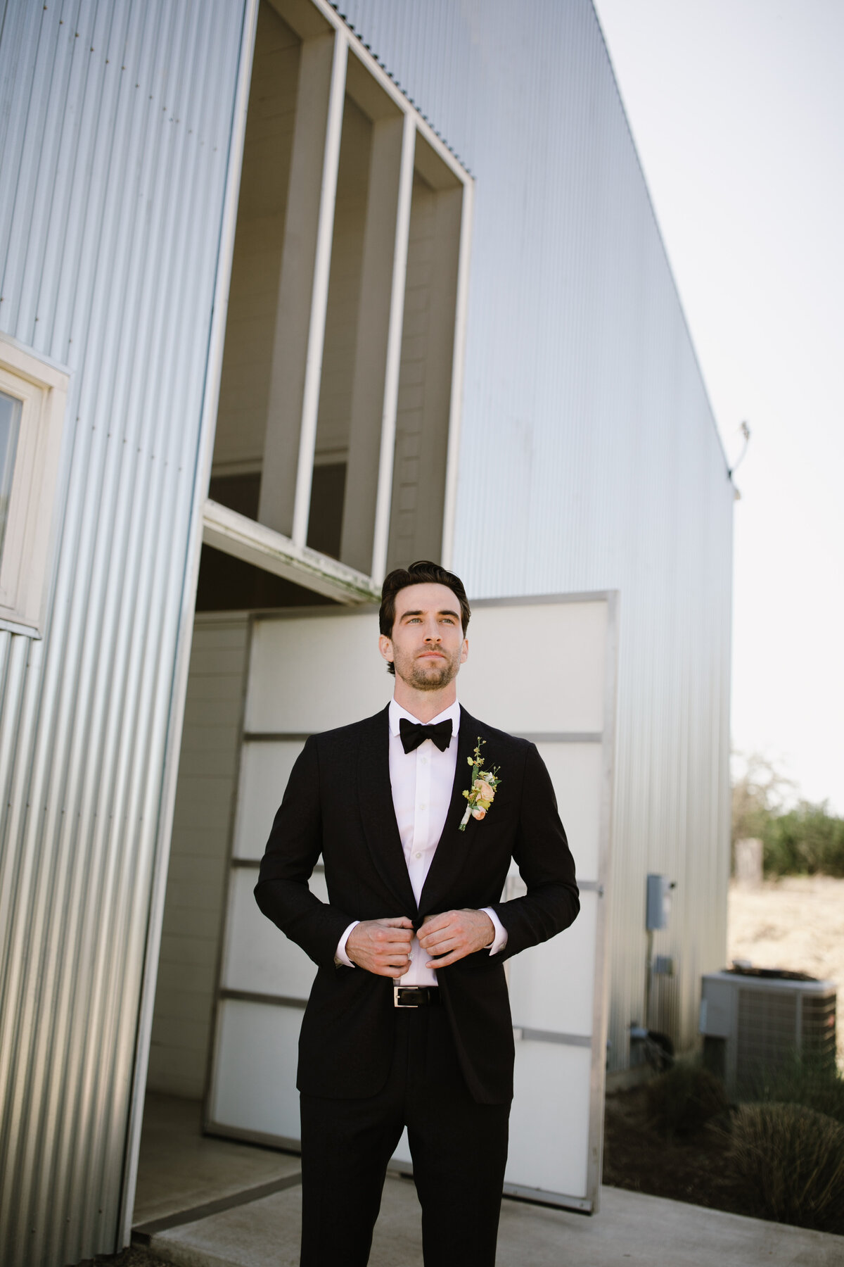 Groom standing outside in black suit at Prospect House, Austin