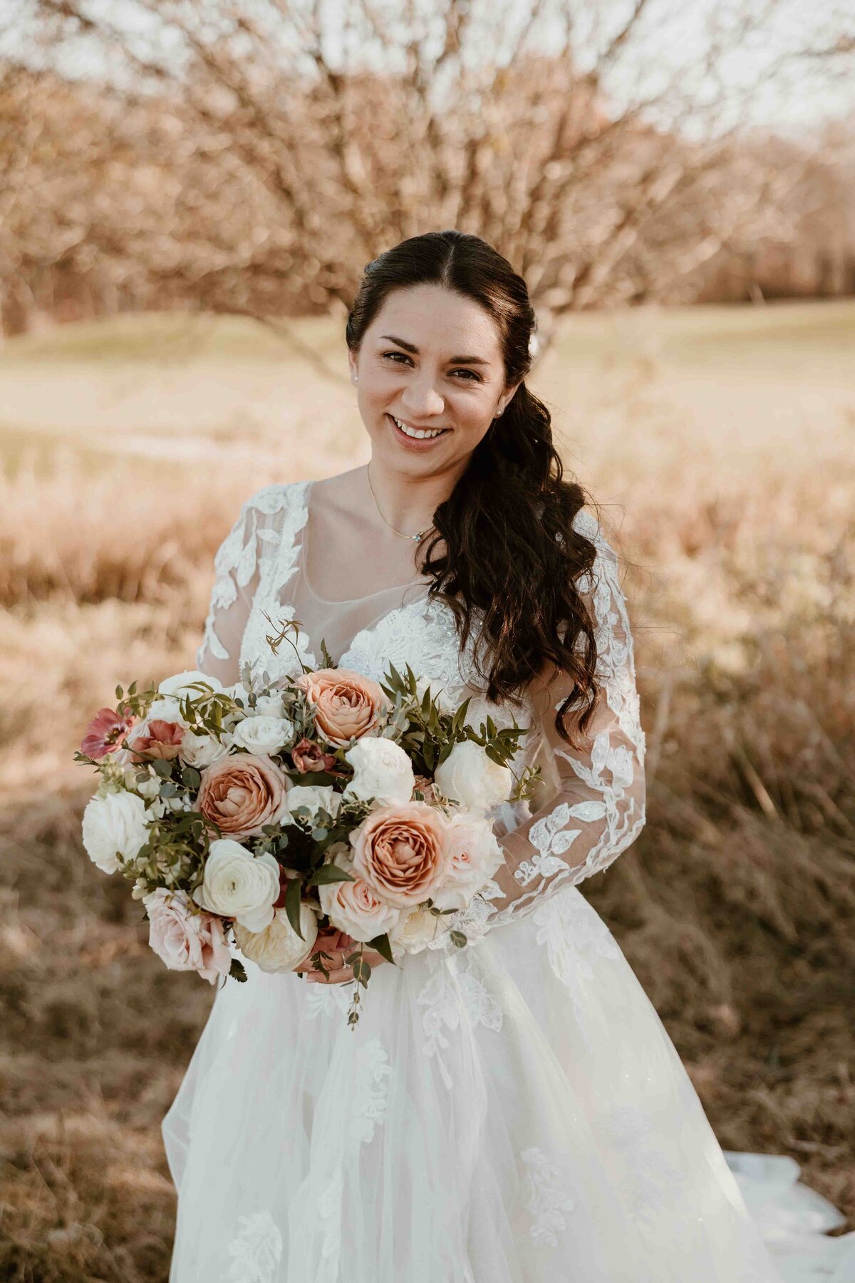 Bride holding bouquet of flowers looking at camera smiling.