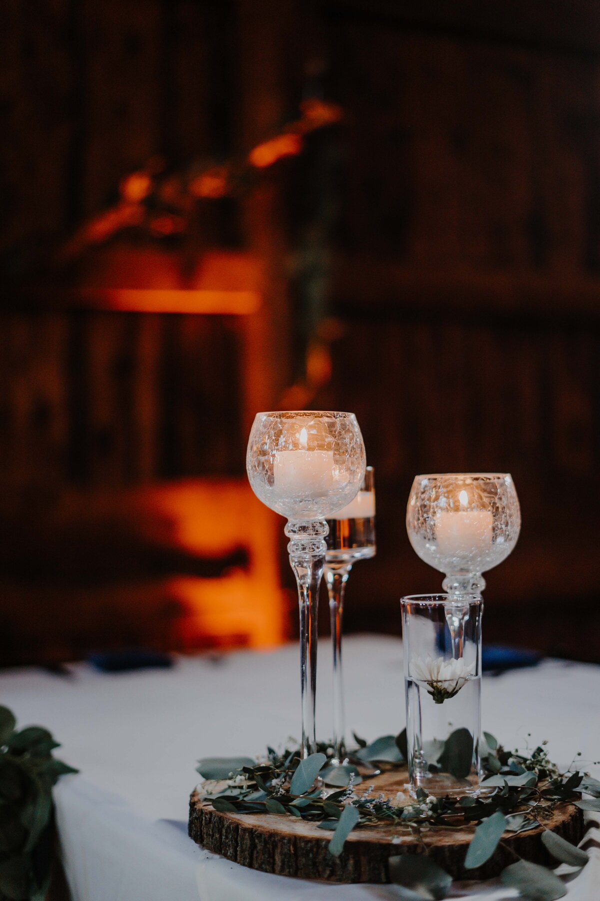 candles inside glasses on top of wood on wedding table centerpiece