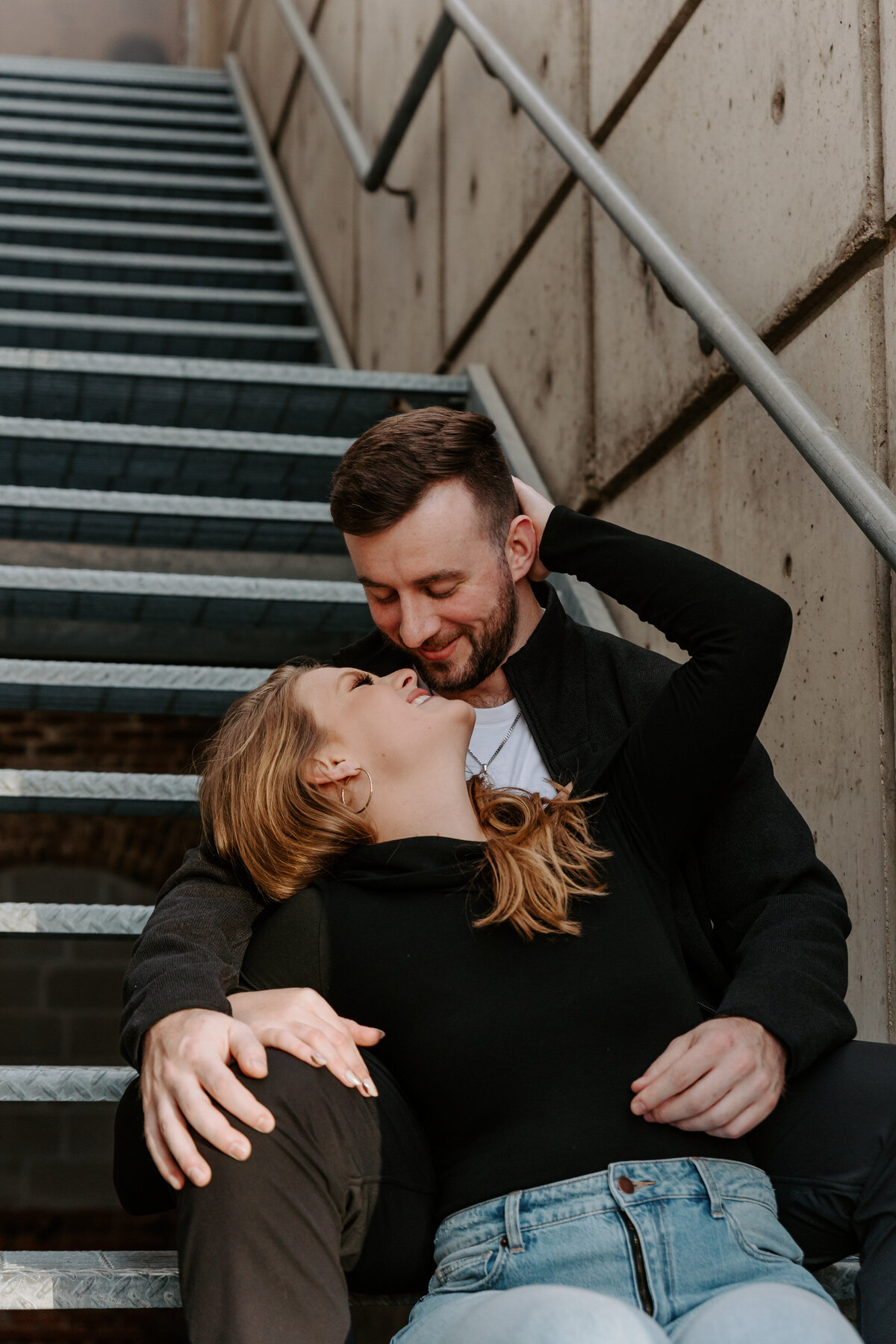 A couple sitting on a staircase together as they are about to kiss