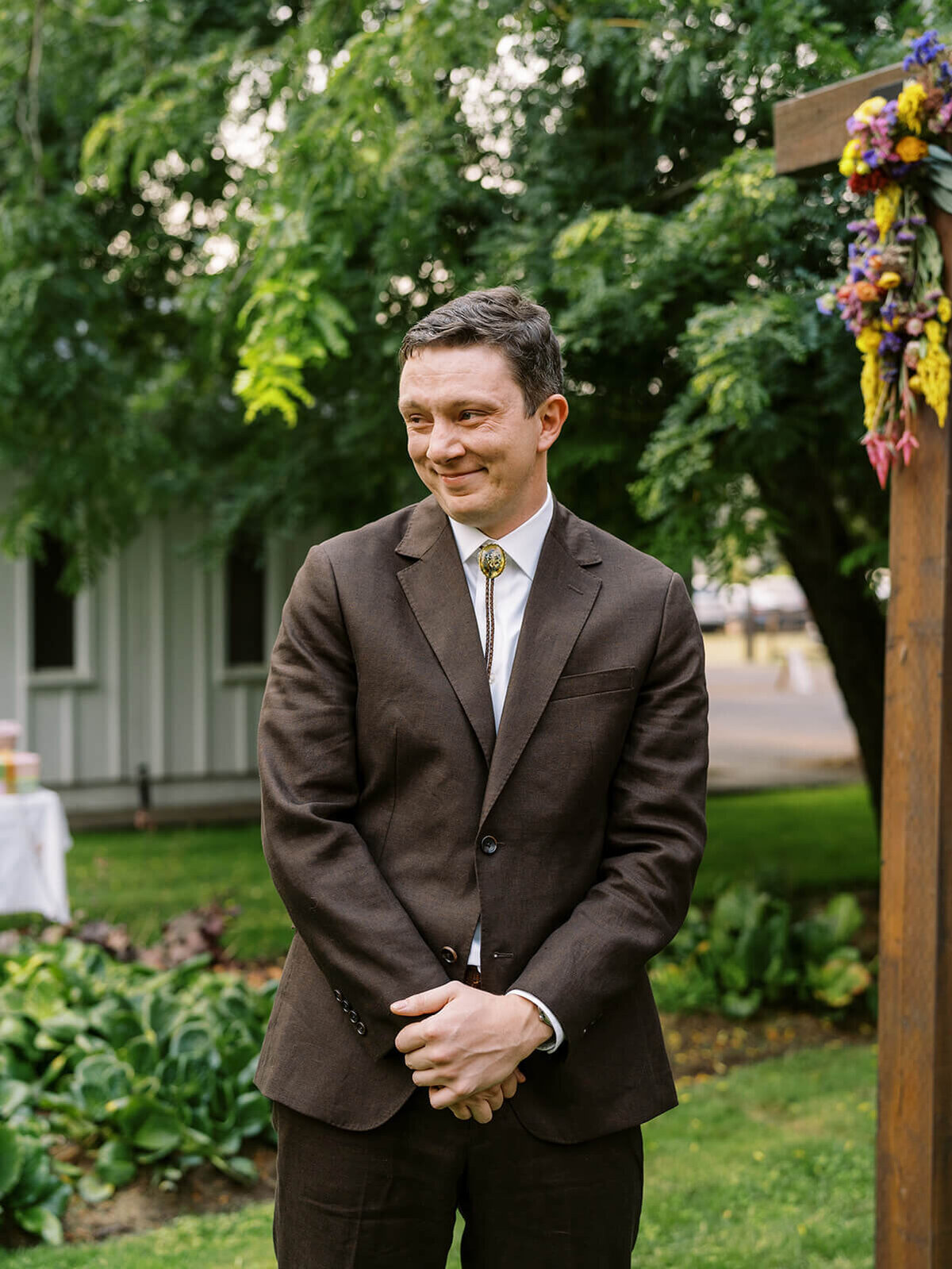 A groom smiling as he sees the bride coming up the aisle. 