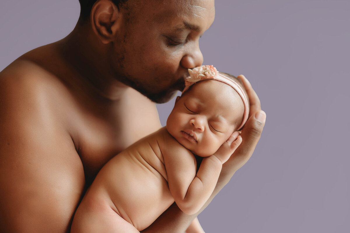 Father kisses his Newborn daughter during Photoshoot in Charleston.