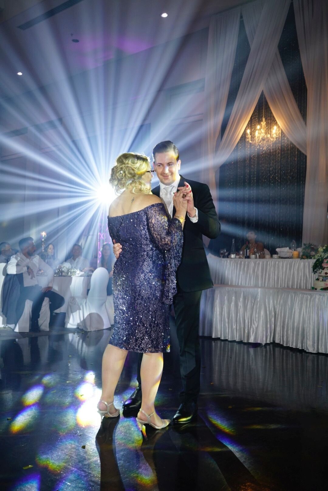 The groom shares a heartfelt dance with his mother during the wedding reception. The intimate moment showcases their close relationship and the joy of celebrating this special occasion together.