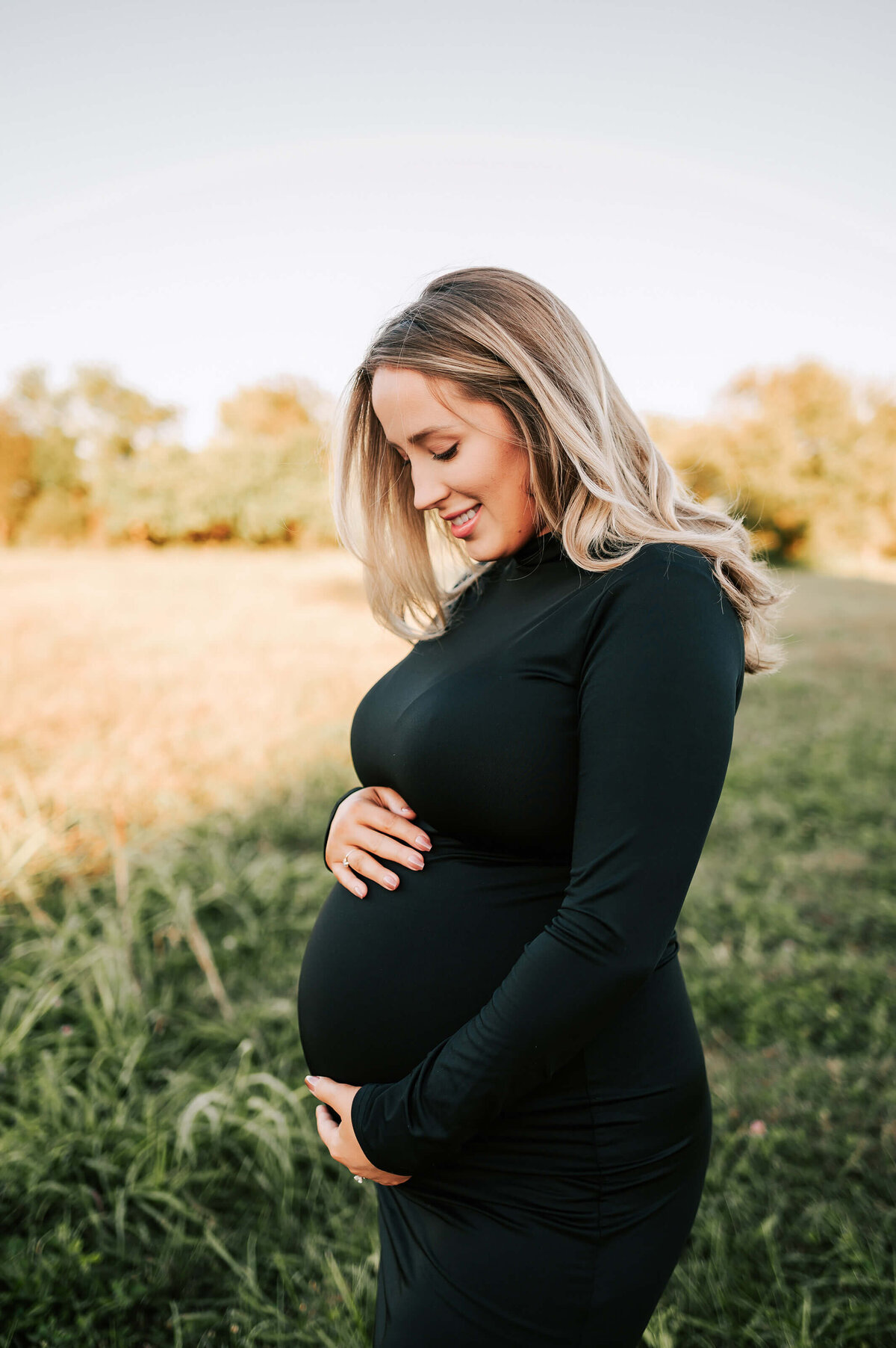 pregnant mom looking down at her baby bump in field in Springfield MO
