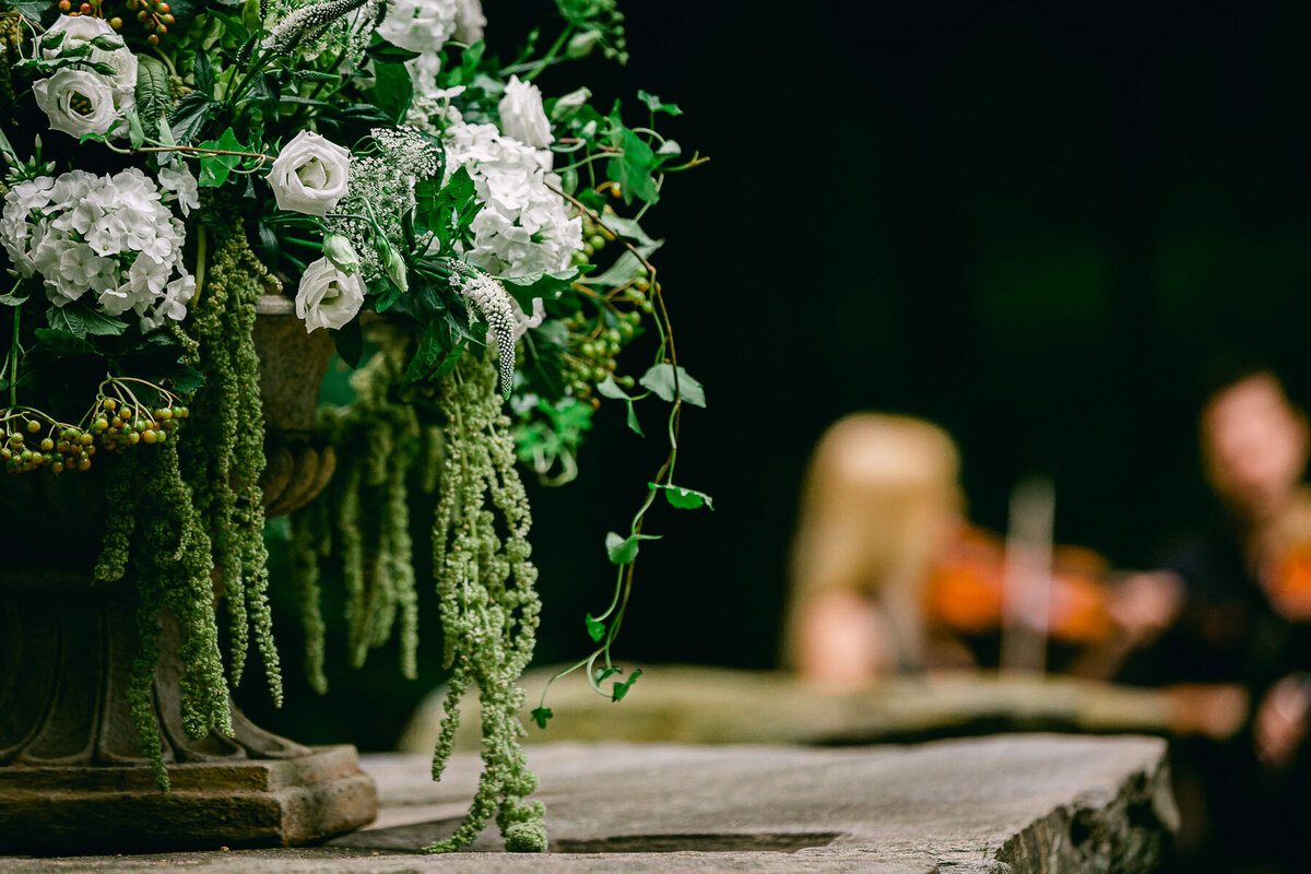 Green and white wedding flowers with ceremony musicians in the background