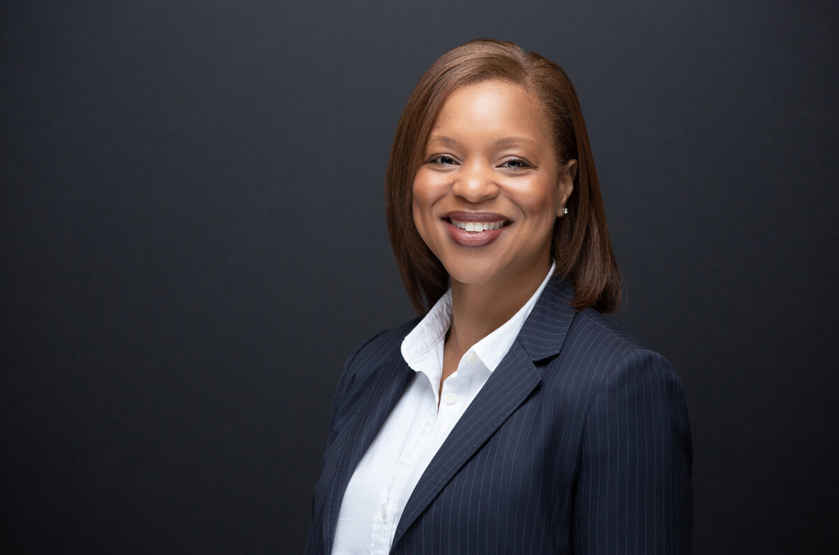African American black female business woman poses for a headshot and personal branding image on a black background taken by Janel Lee Photography in Cincinnati Ohio