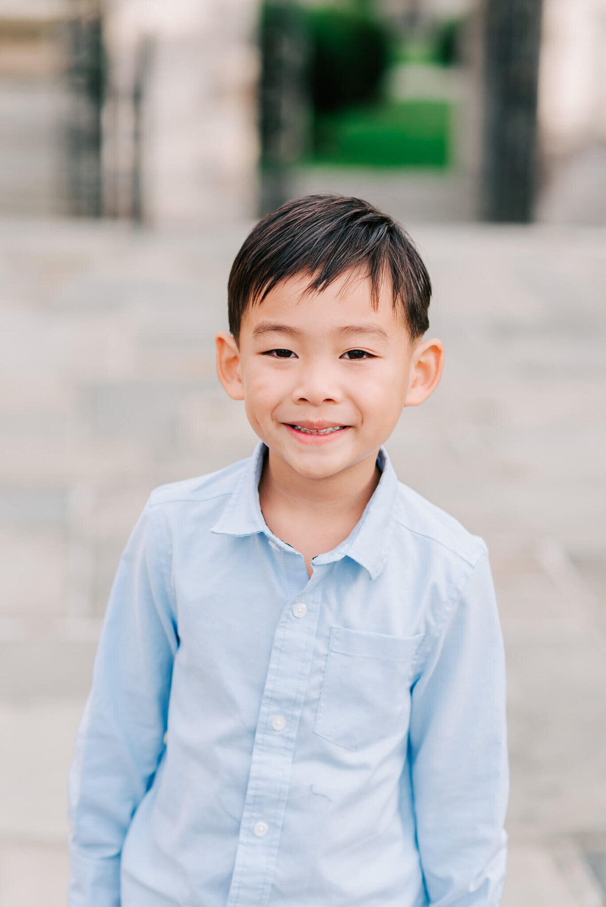 An outdoor Denise Van Photography portrait of a young boy wearing a blue button-down