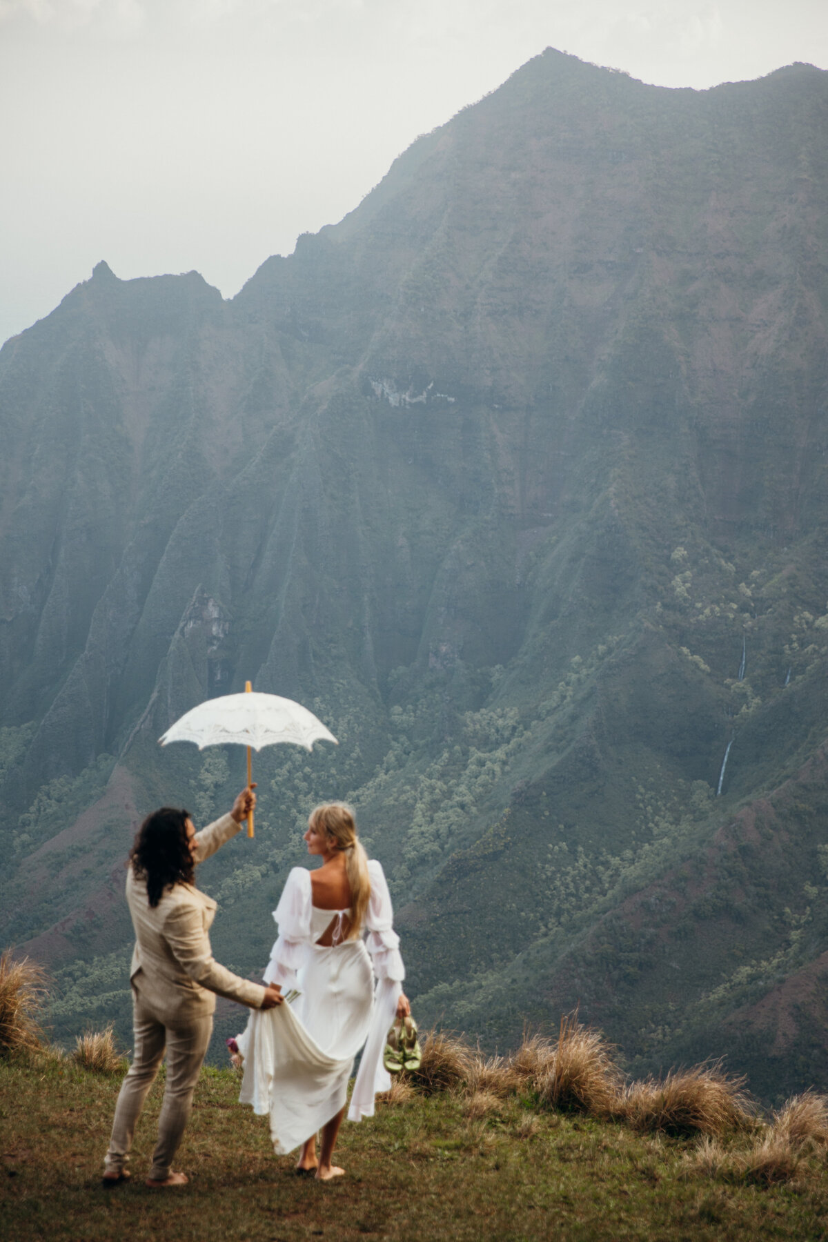 Maui Wedding Photographer captures groom holding umbrella while walking cliffside