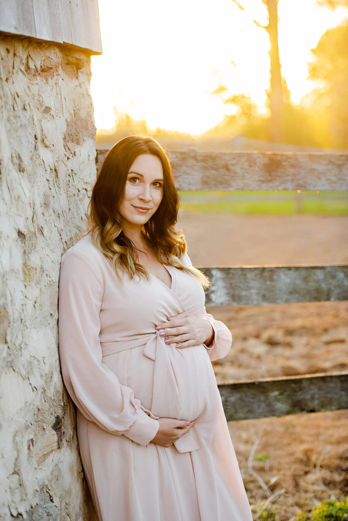 pregnant woman leaning against a wood barn for her outdoor maternity photography session