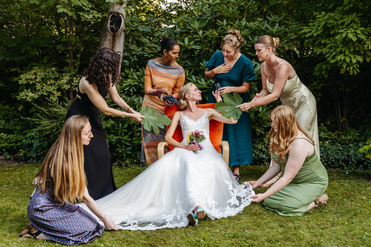 Bride surrounded by friends adjusting her dress