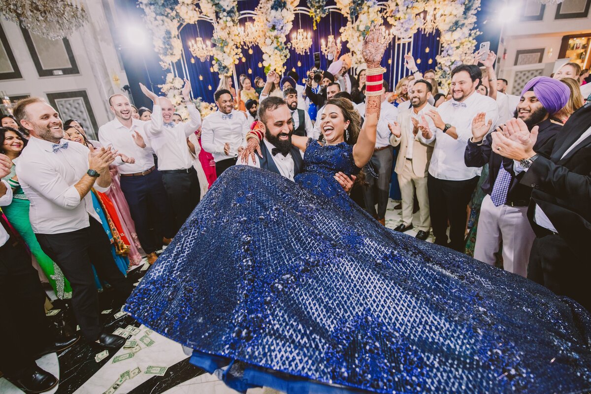 indian groom carrying and spinning the bride on the dance floor during their wedding reception