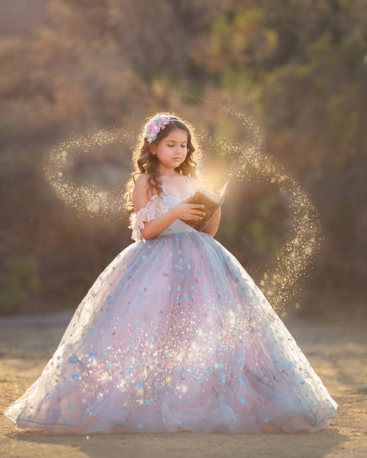 Fine art photograph of little girl in couture gown reading a book with bagical stars - Los Angeles Children’s Photographer