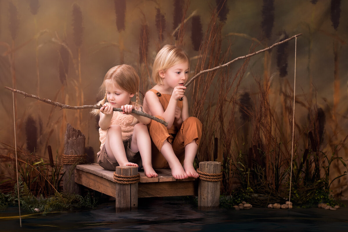 Serene portrait of two young children sitting on a rustic dock, fishing in a natural and tranquil setting. Captured in Overland Park, Kansas, this peaceful and nature-inspired setup is perfect for families seeking artistic child photography.