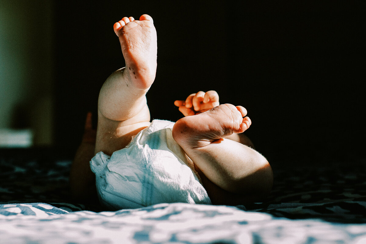 loveland Colorado newborn baby's feet glow in sunlight while baby lies on a bed