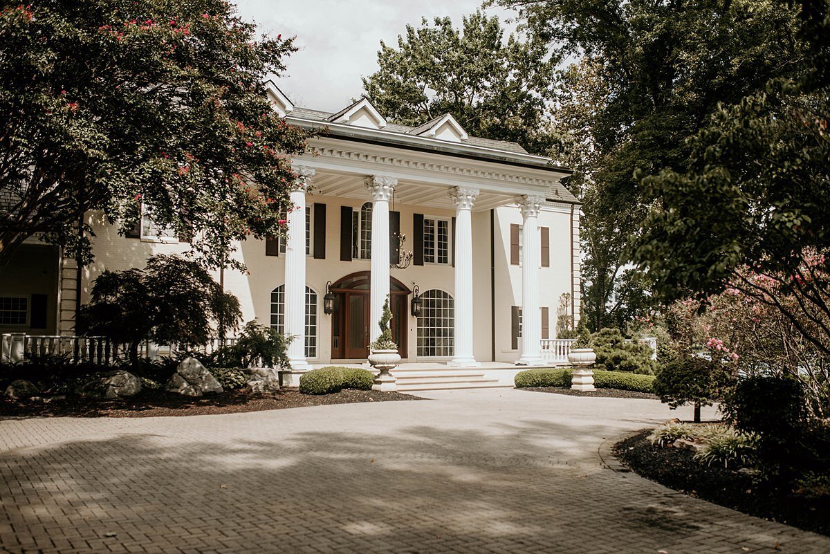 large white mansion in Nashville set amongst large green trees on a circular driveway.
