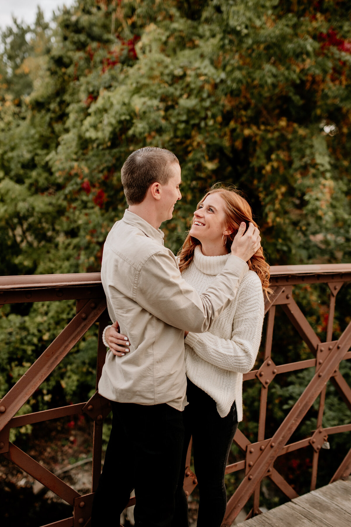 Cozy Fall engagement photos in Downtown Minneapolis on an iron bridge, with Fall foliage framing the couple.