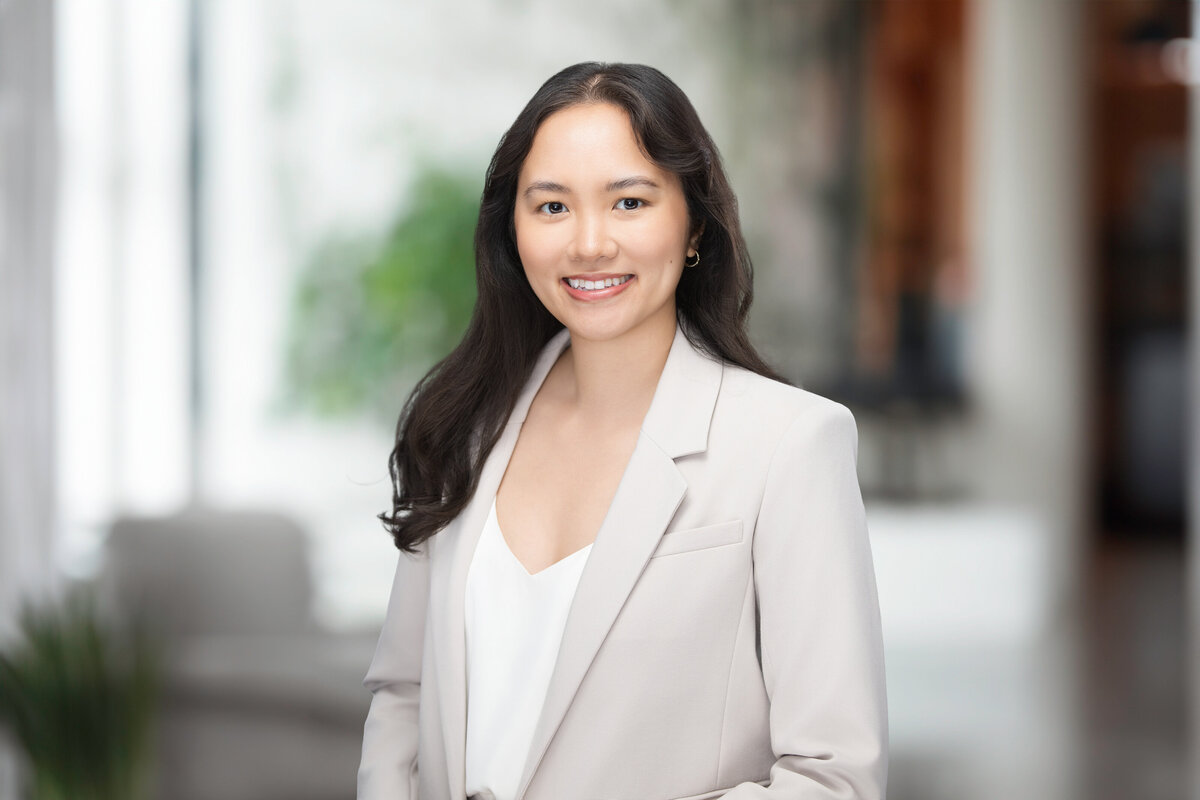 Professional headshot of a young woman smiling confidently in a light beige blazer and white blouse, captured against a clean gray backdrop at Janel Lee Photography in Cincinnati, Ohio. This polished portrait was created for medical residency applications, highlighting a professional yet approachable look ideal for residency program submissions.