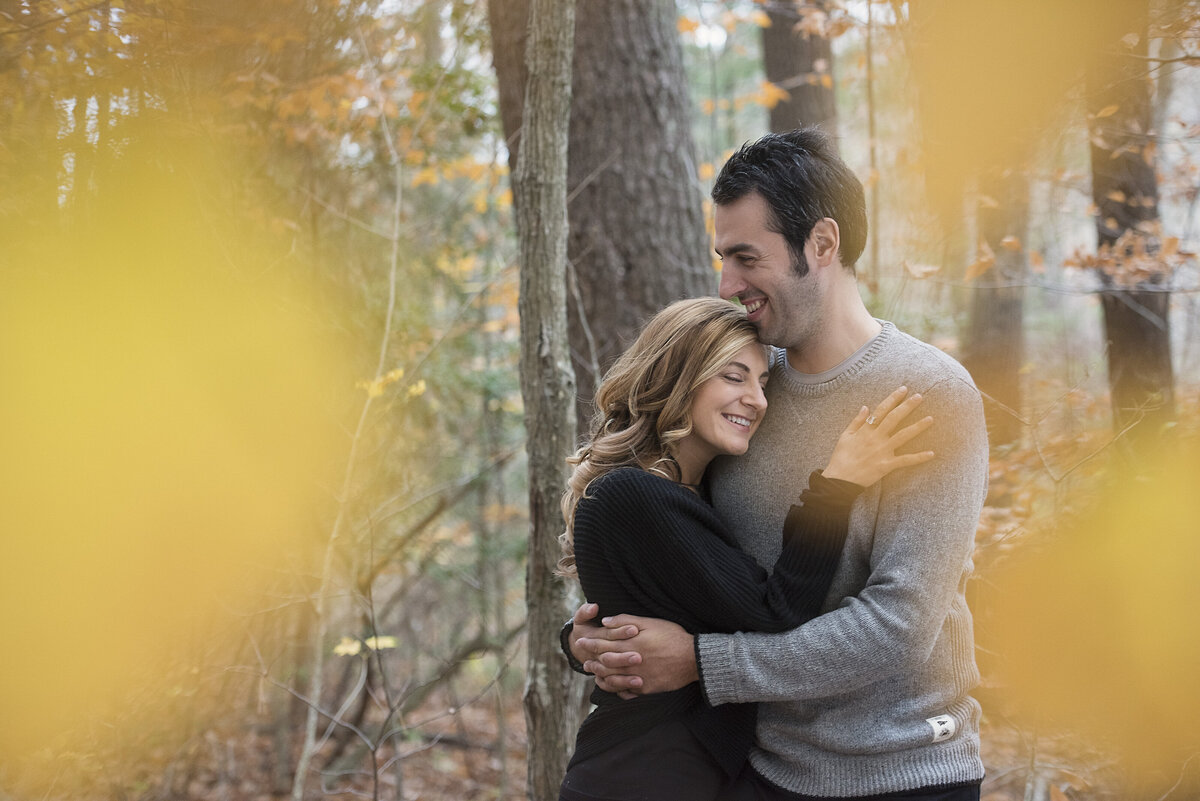 A couple hugging while standing in a wooded area