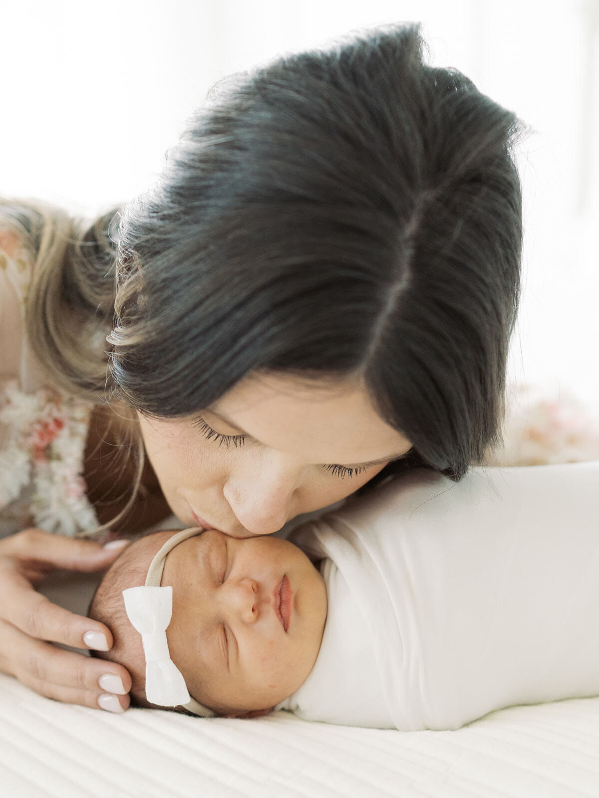 A mother lying on her bed, tenderly kissing her newborn baby, with a peaceful and loving expression