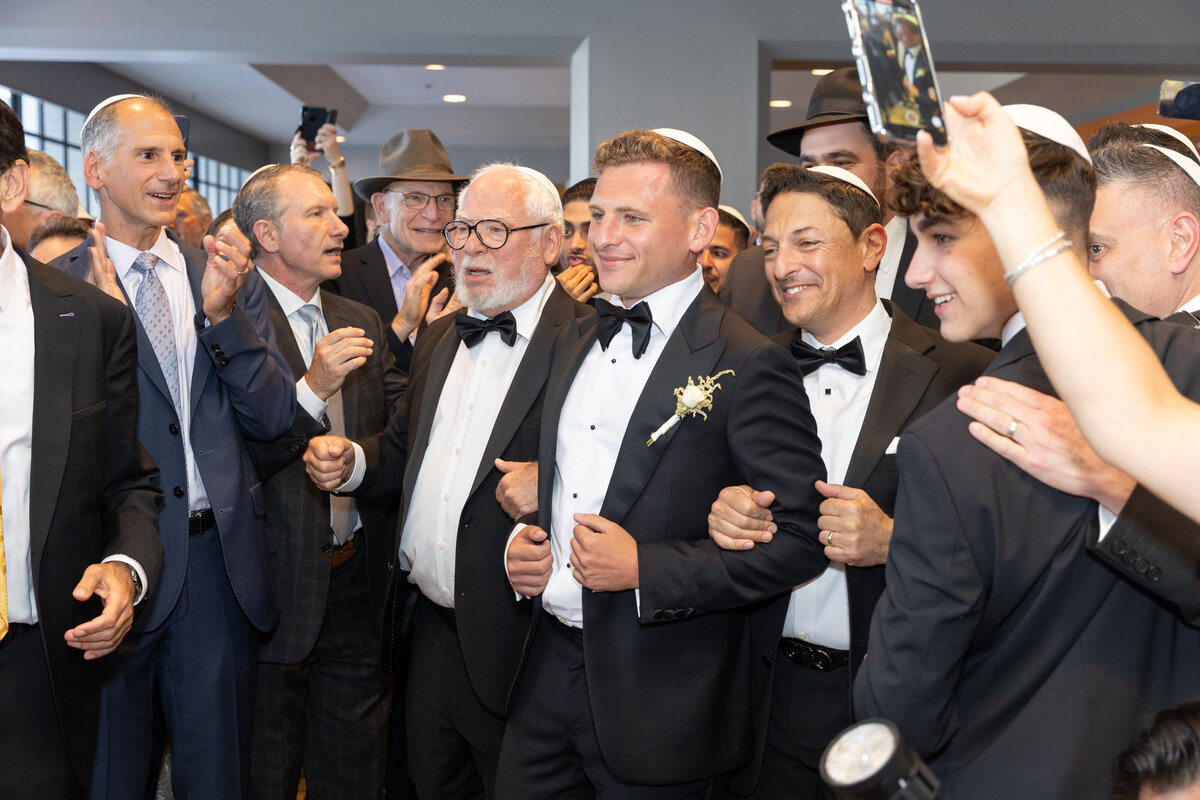 A groom walking arm in arm with his groomsmen