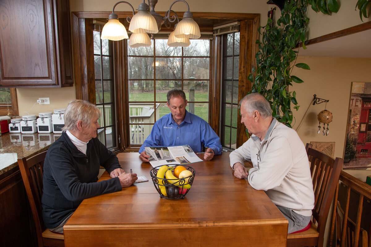Three men are sitting at a table with a basket of fruit on it