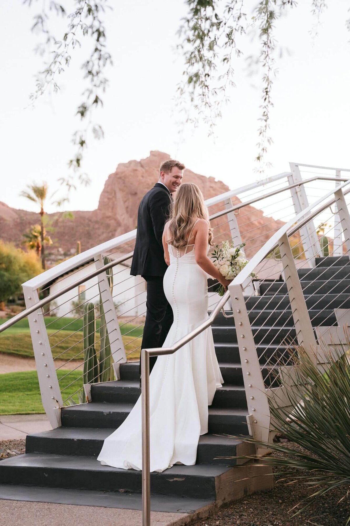 Bride and groom walking up the staircase at Mountain Shadows in Scottsdale, with Camelback Mountain in the background at sunset.