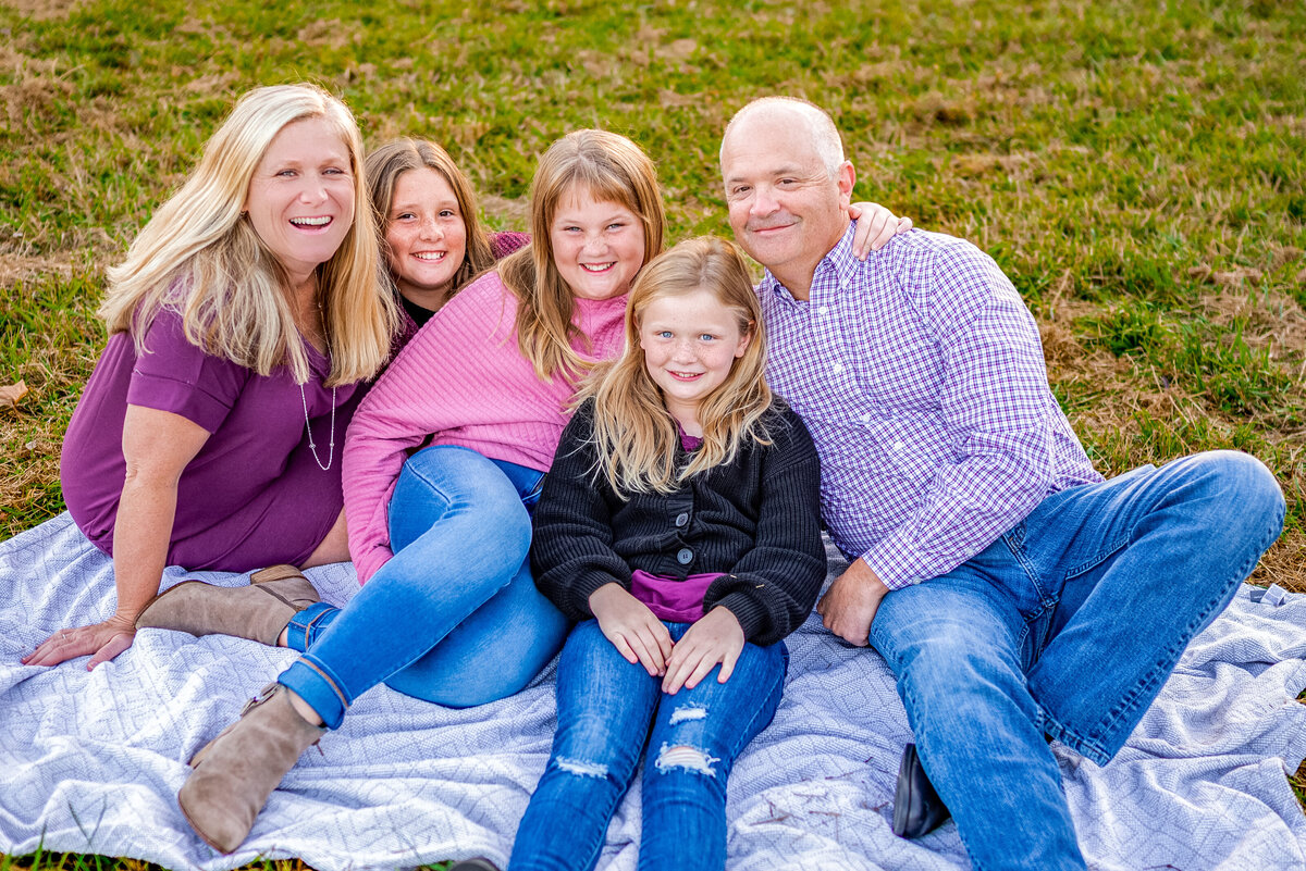 A family cuddles on a blanket for family photos at Hayes Nature Preserve in Huntsville Alabama