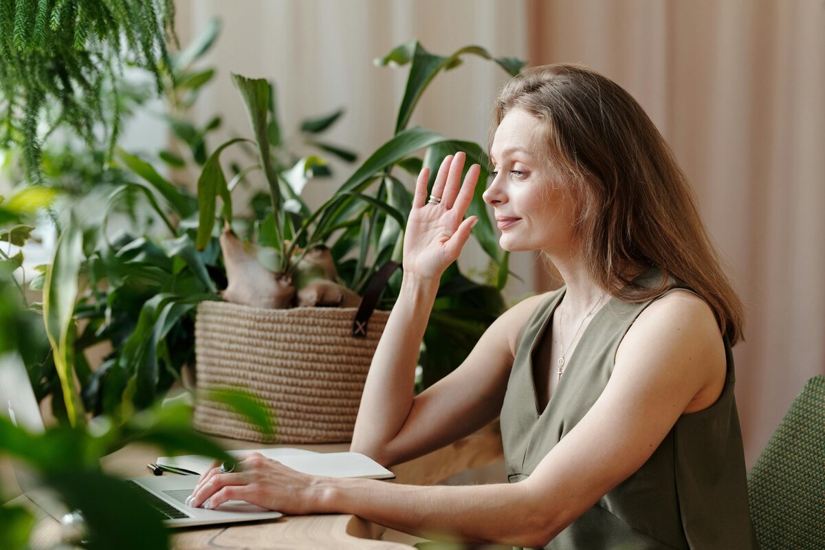 woman on computer smiling and waving on a video call