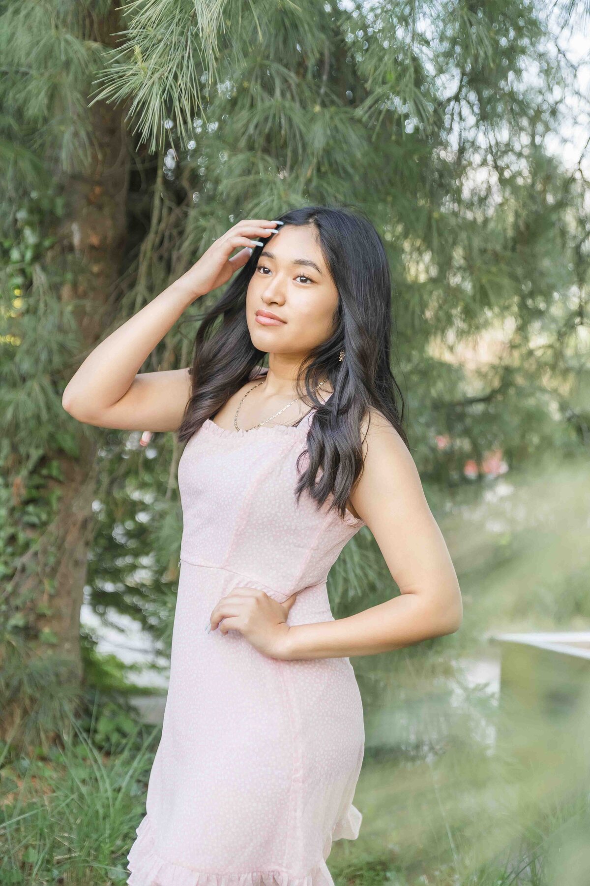 Senior Girl in pink dress pushing he hair back from her face