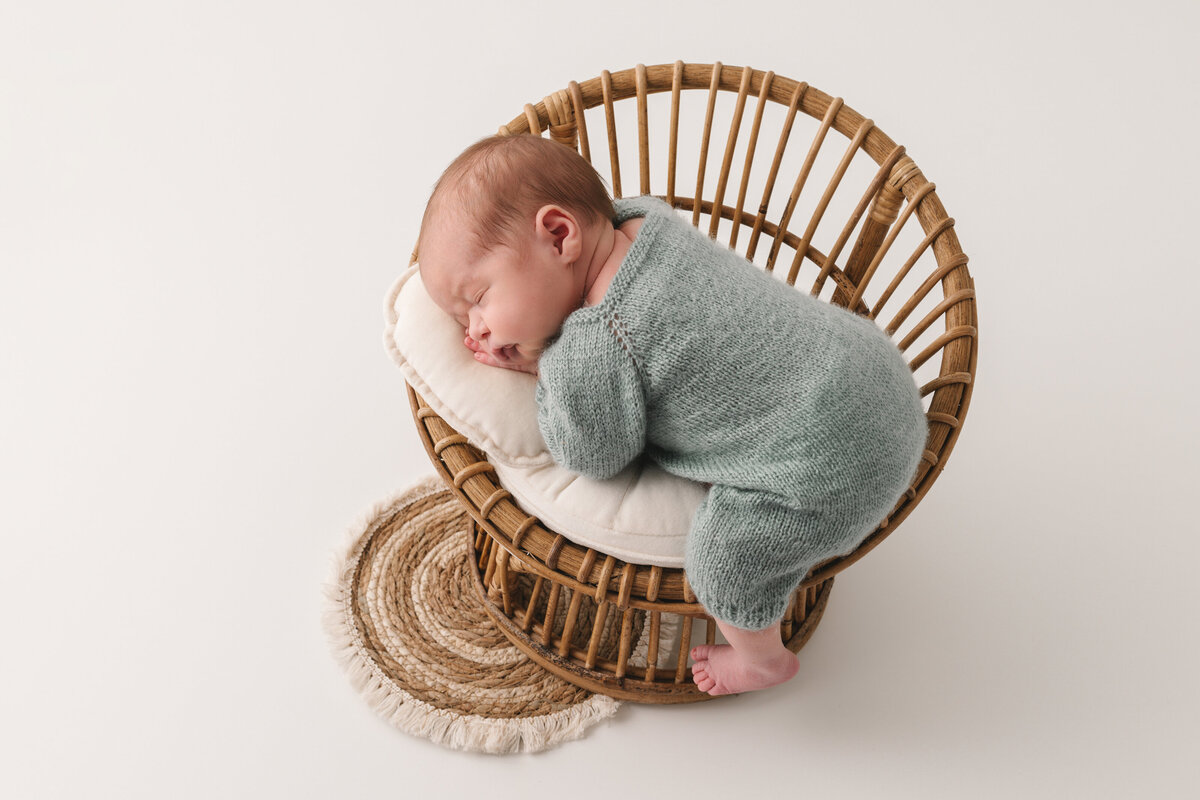 pasgeboren baby jongen in groen setje op een stoeltje in neutrale setting