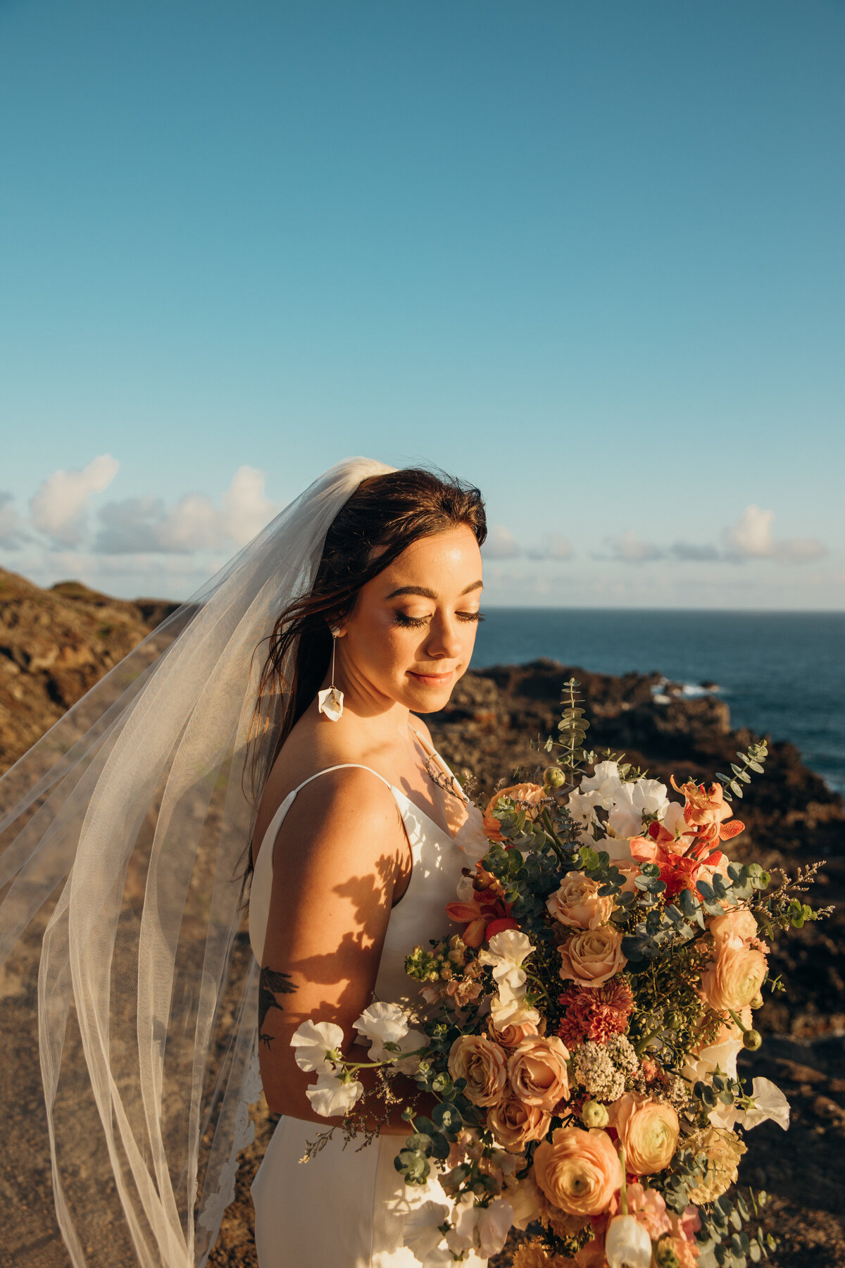 Maui Wedding Photographer captures bride holding bridal bouquet with veil blowing in wind