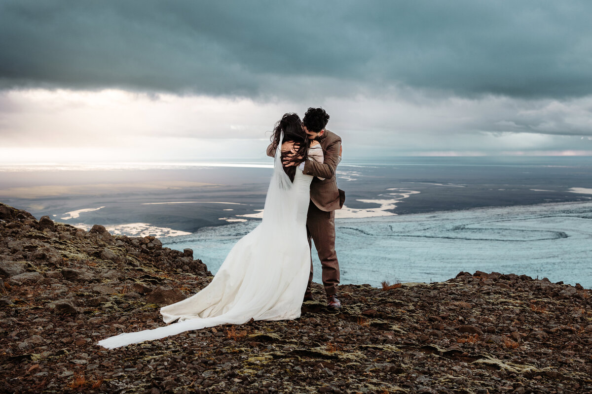 A couple embraces warmly, enveloped by the mystical fog at Iceland’s Lake Myvatn, creating a serene and romantic wedding portrait.