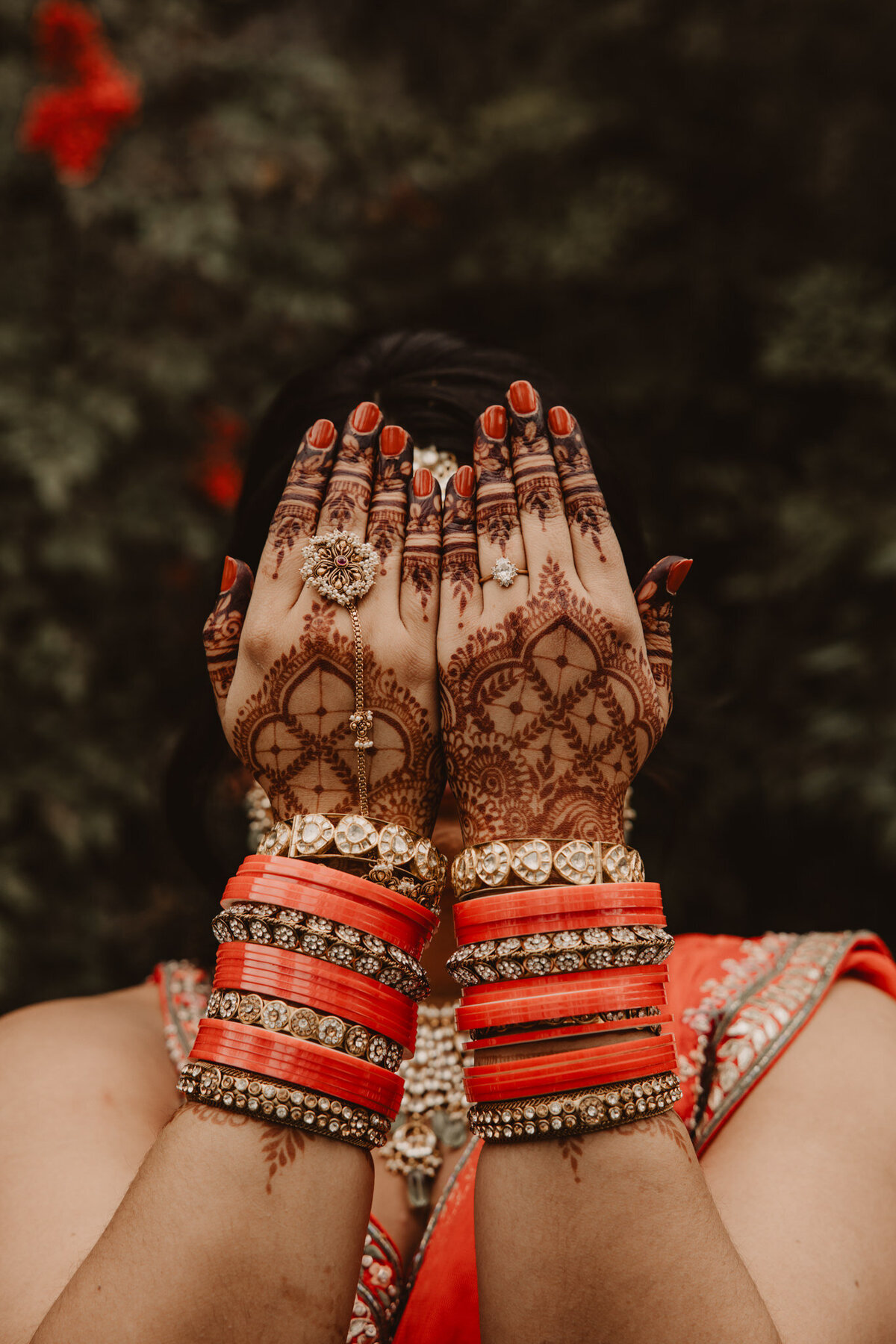Hands covered in henna tattoo held in front of someone's face