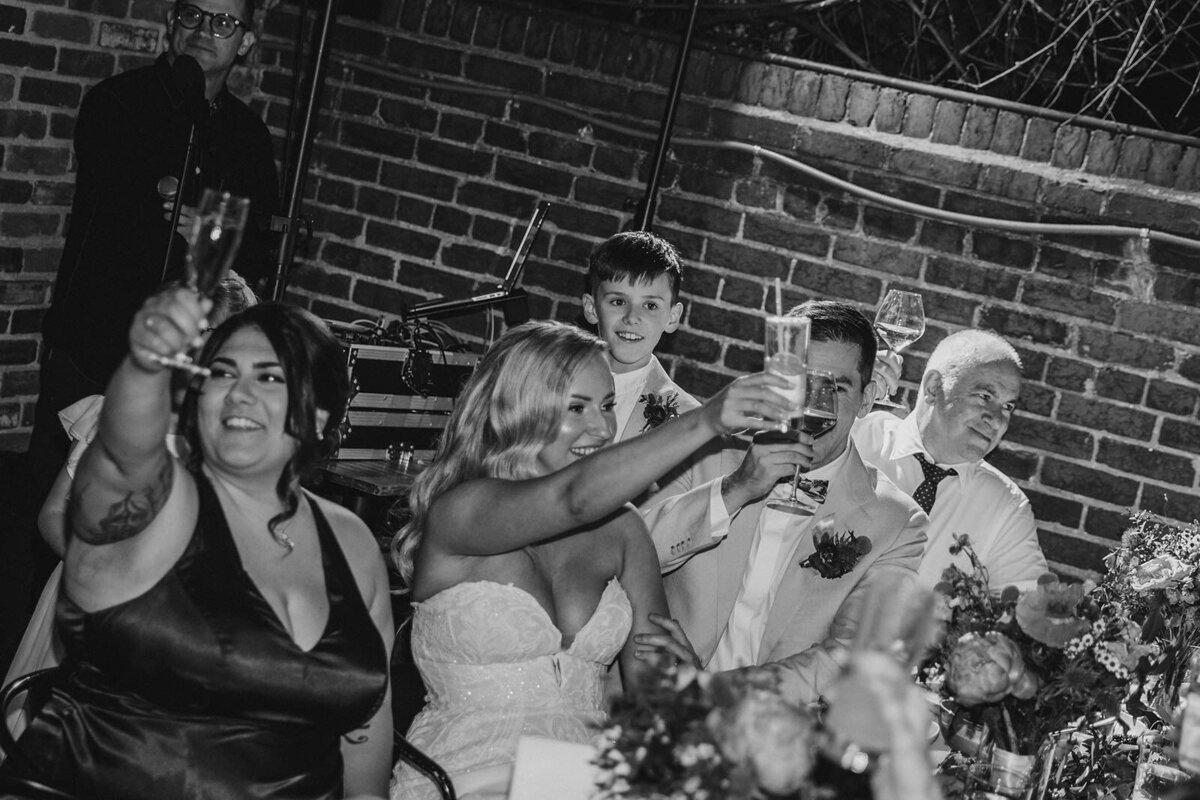 Newlyweds and their guests raising their glasses in a toast 