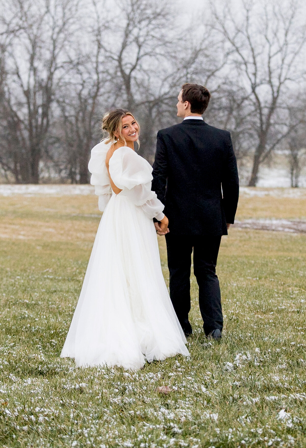 bride in a snowy field wearing couture wedding dress with puffy sleeves