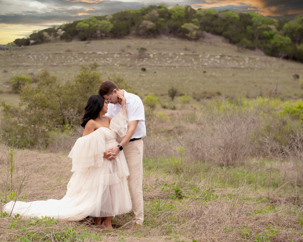 Maternity couple photography featuring expecting parents embracing in natural outdoor setting