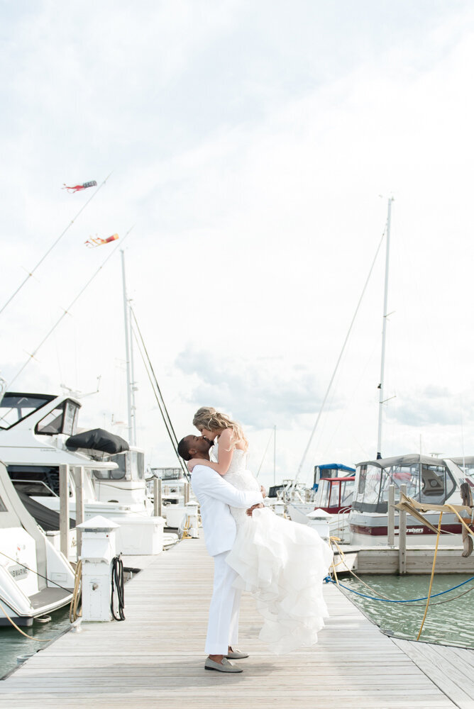 groom lifting bride while kissing at yacht club