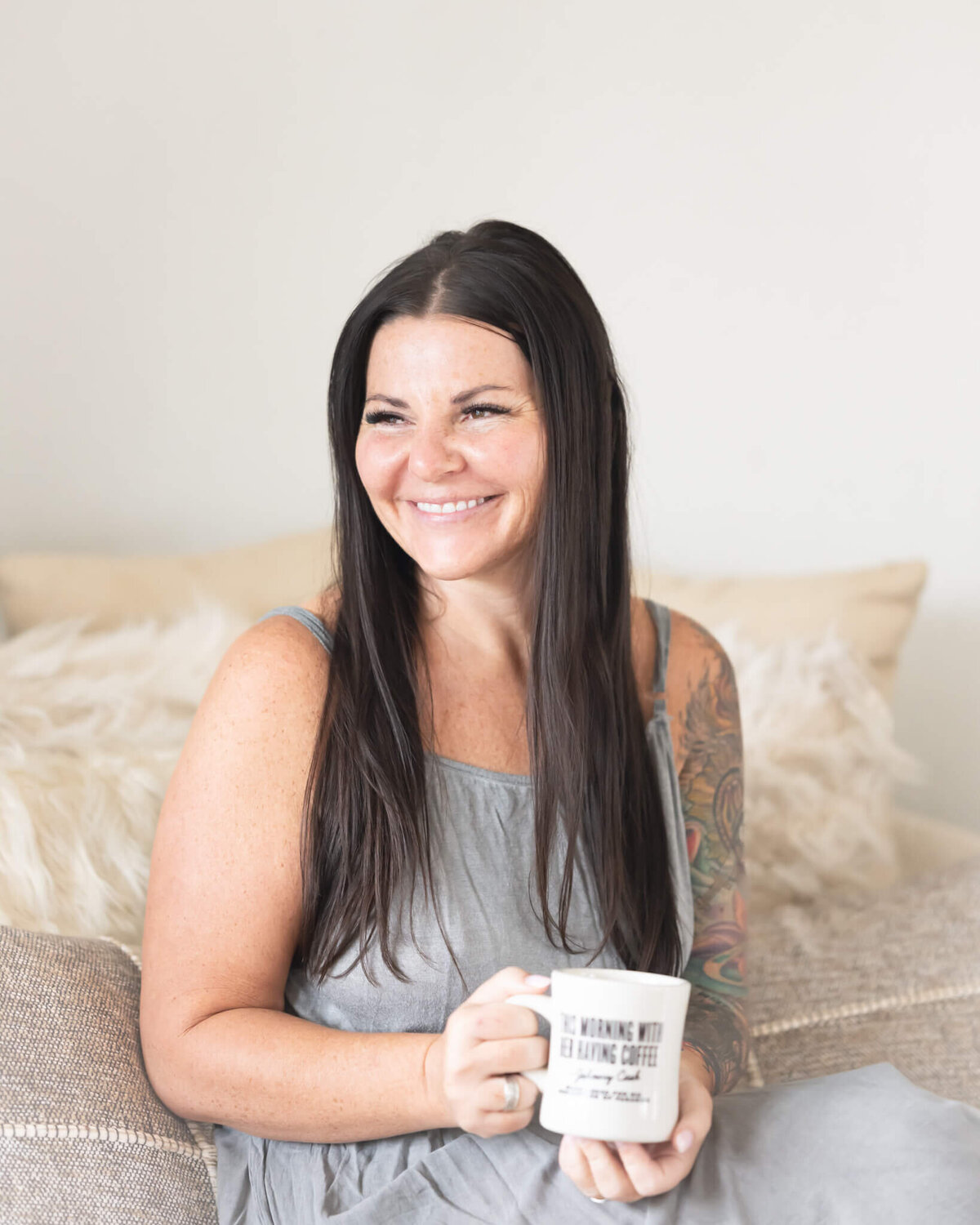 Speaker, coach and leadship expert drinking coffee in grey next to the window smiling