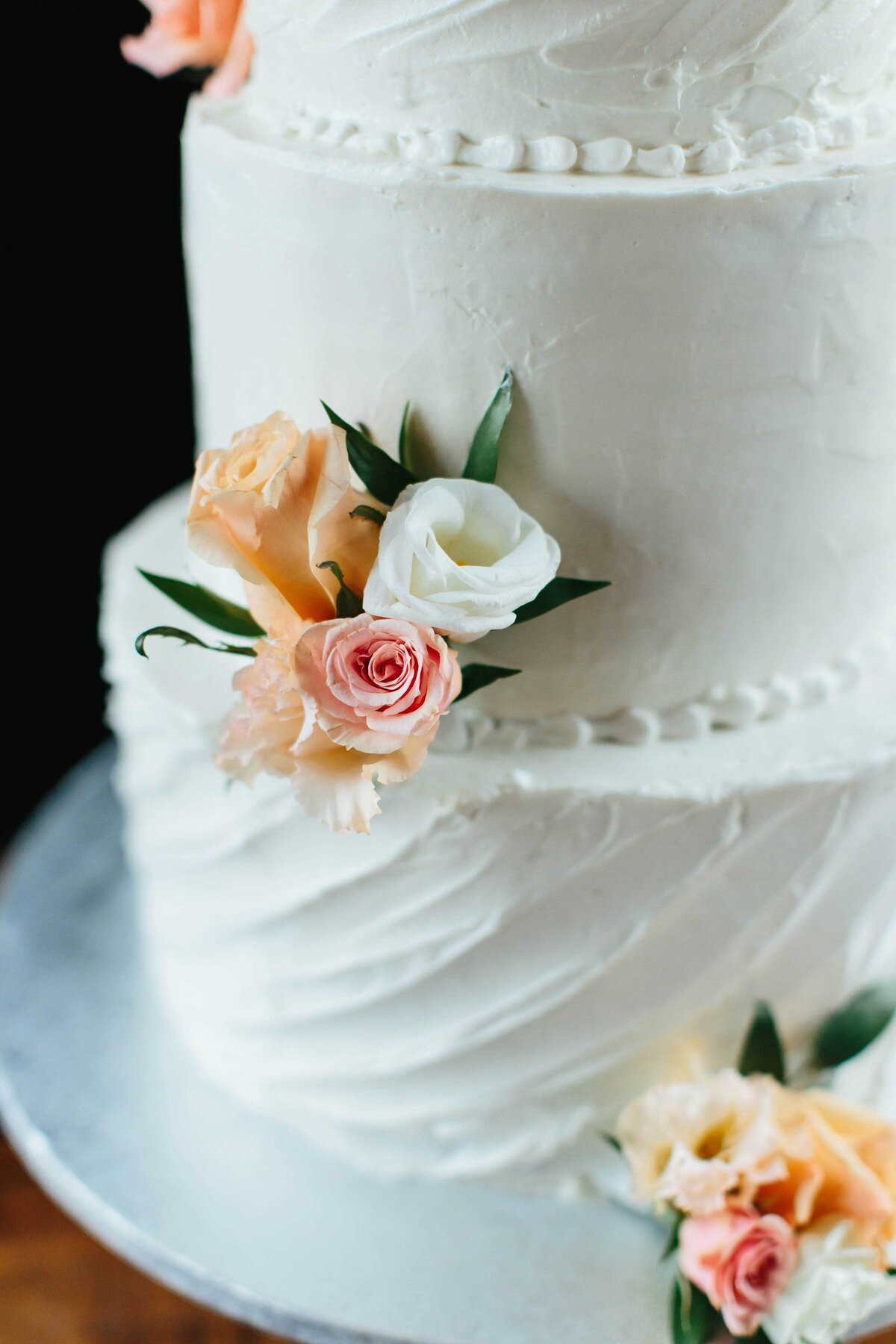 Close up detail picture of wedding cake with white and orange flowers
