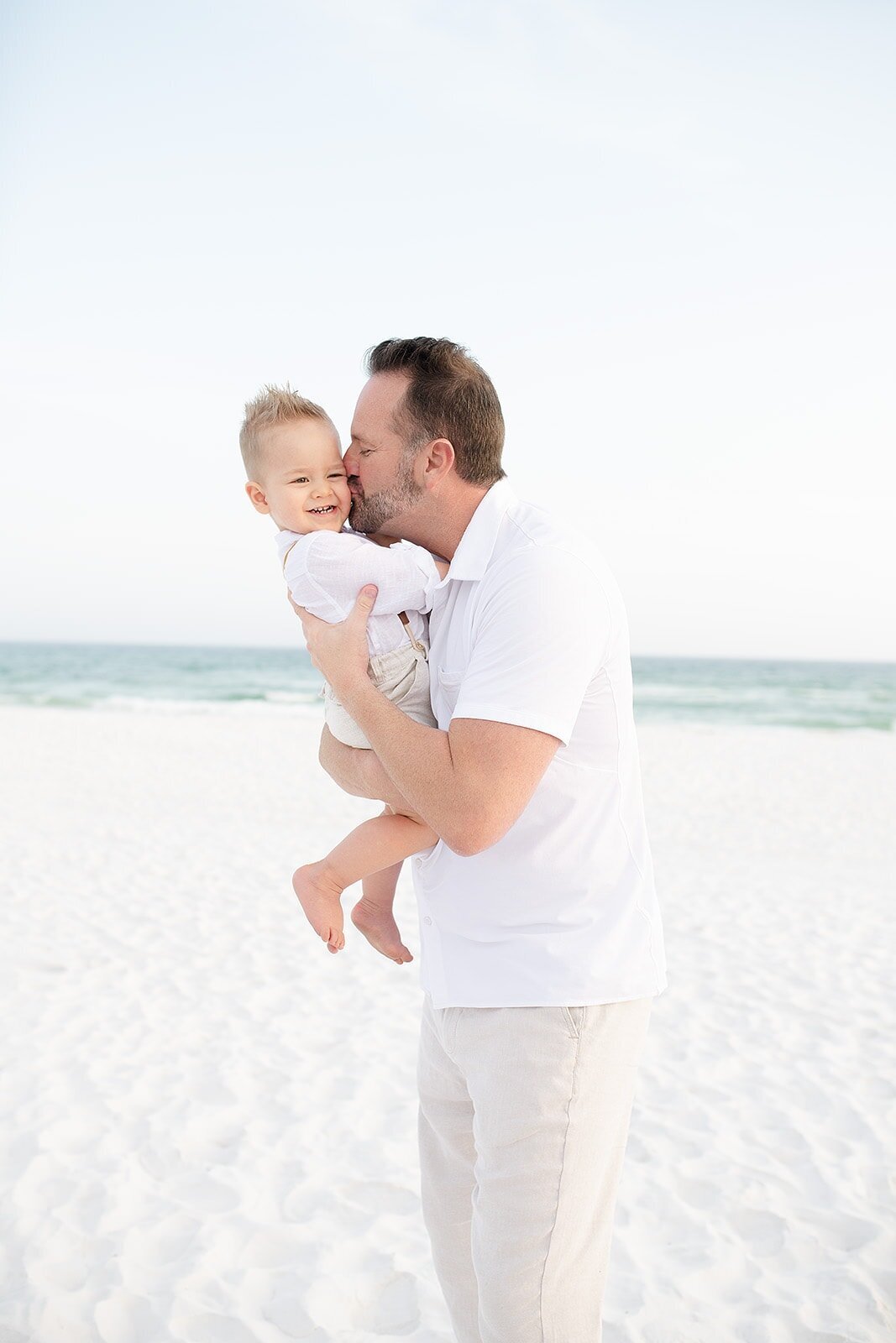 father kissing his toddler on the cheek at the beach