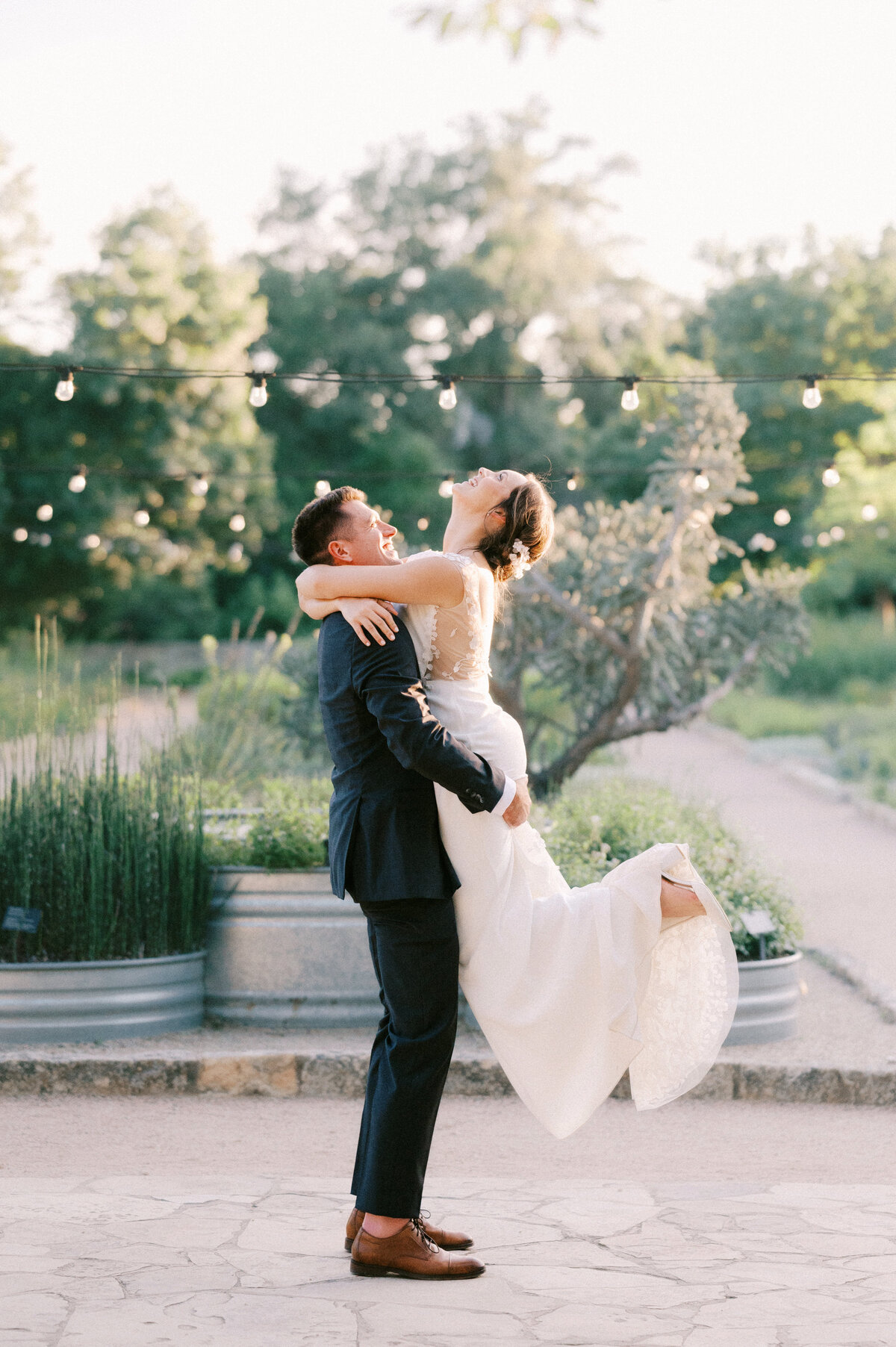 wedding portrait with groom lifting bride into the air at ladybird johnson wildflower center by austin wedding photographer