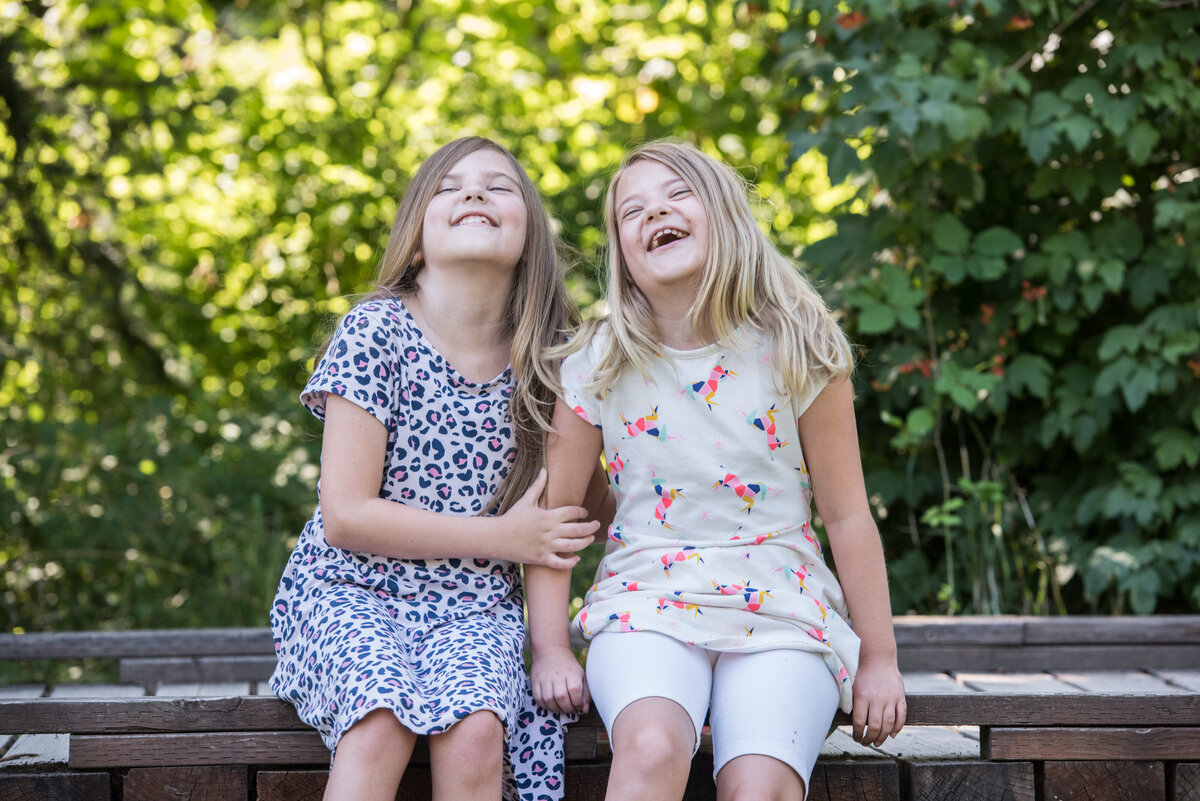 Two girls sitting on a bench laughing