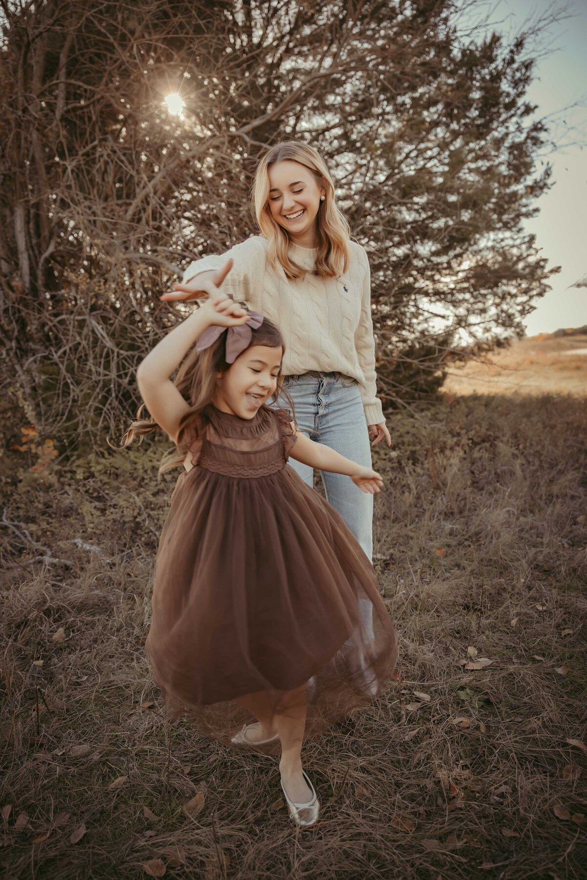 teenage daughter holding her younger sister's hand and twirling her around.