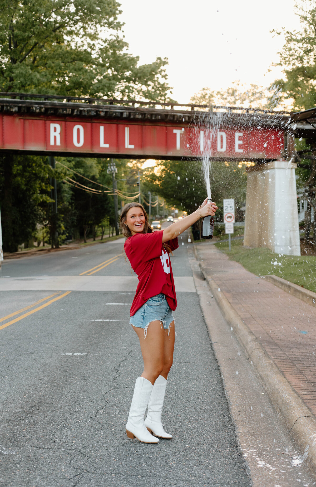 UA grad popping champagne at the roll tide bridge