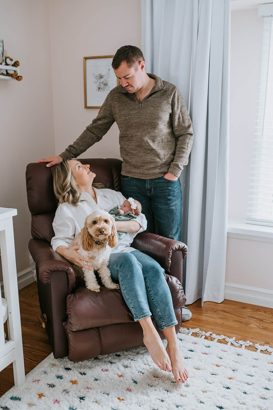 Mother-sits-on-chair-with-newborn-and-dog