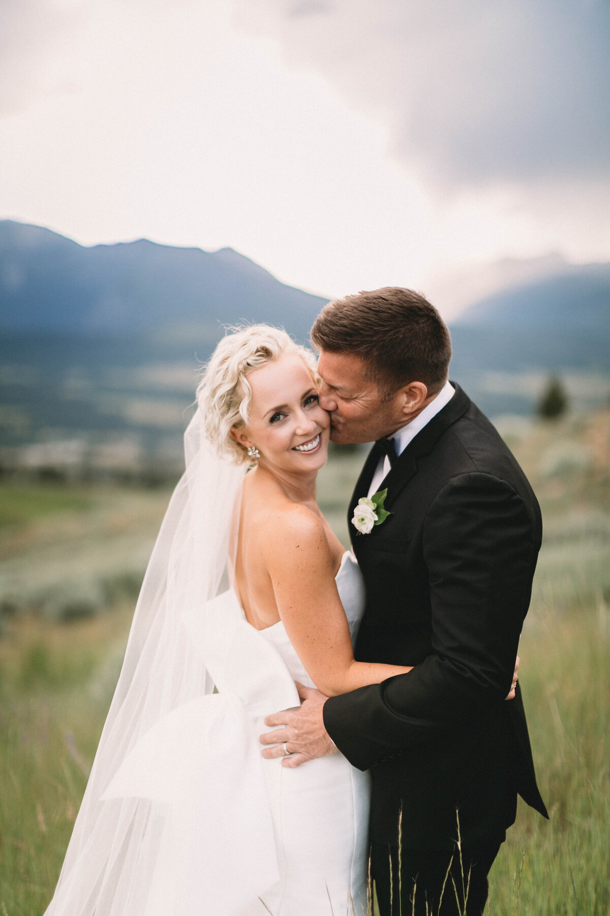 groom kissing bride on cheek