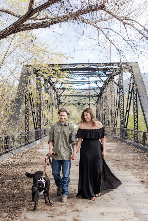 engaged-couple-walking-with-dog-on-Sweetwater-River-Bridge-San-Diego