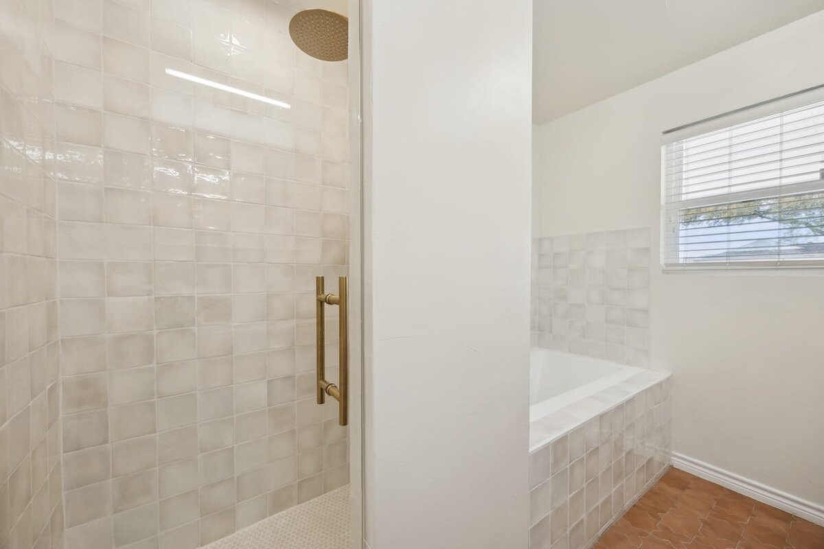 Tile detail of walk-in shower and soaking tub in the primary bathroom at 3120 Chapel Downs Dr Dallas TX with brass hardware — Haven Realty Group.
