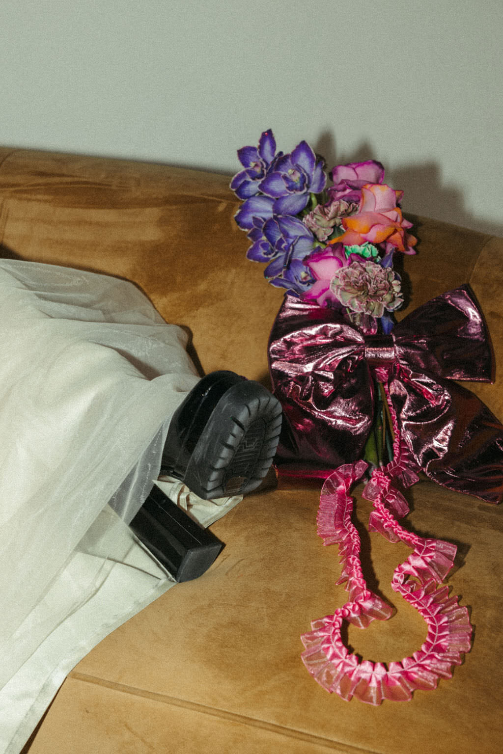 A foot with a boot on next to a bouquet of flowers.